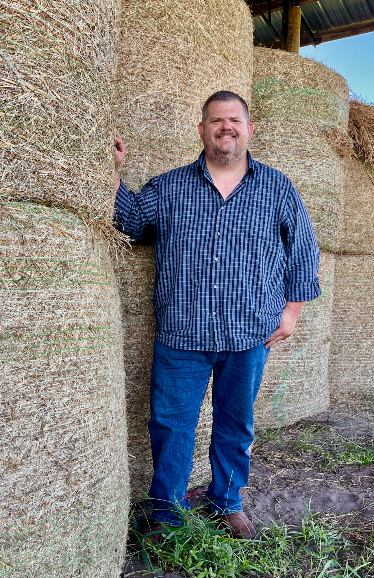 Photo of Don Tanner standing in front of hay bales