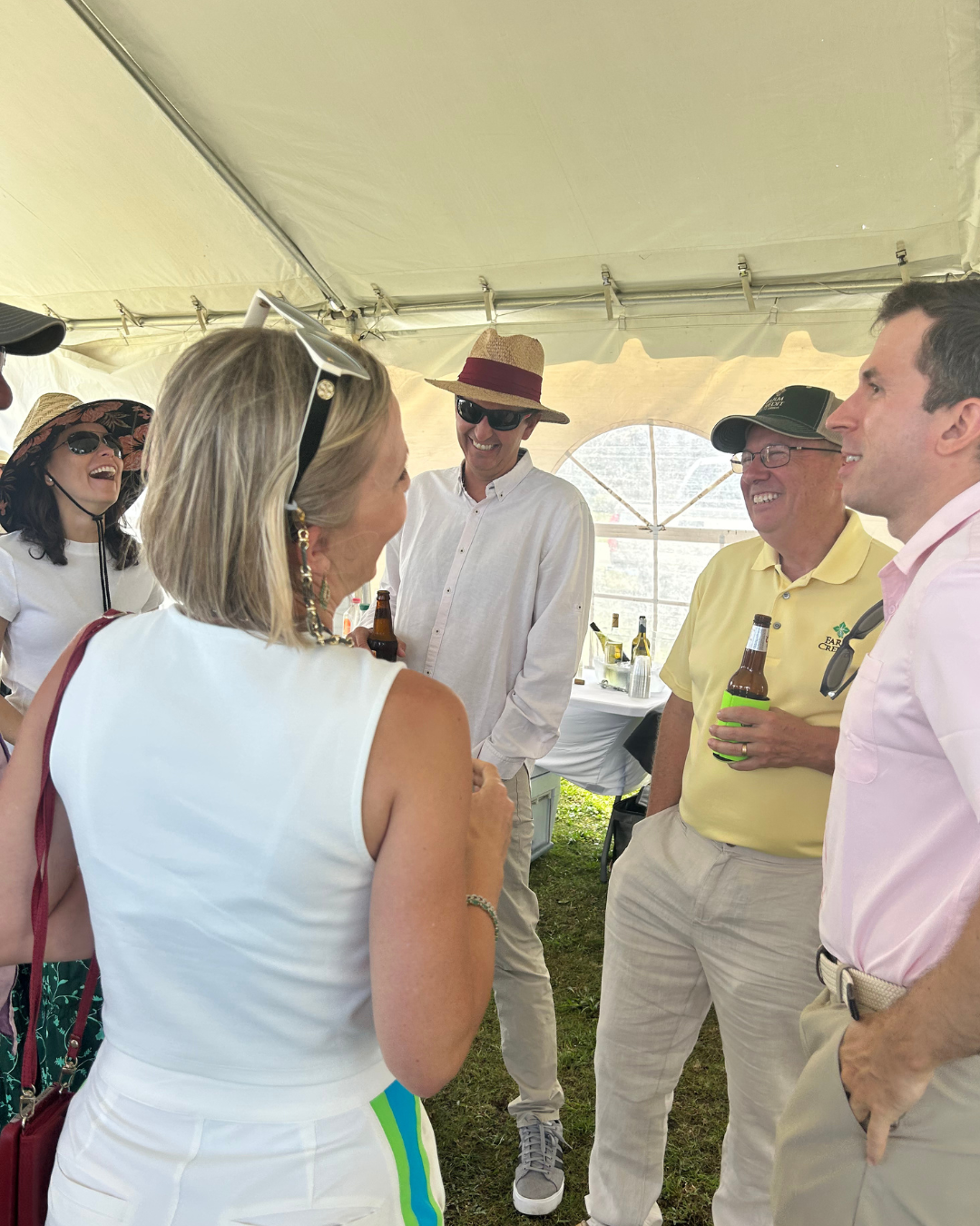 A group of people gathered under a tent at an outdoor event, engaged in conversation.